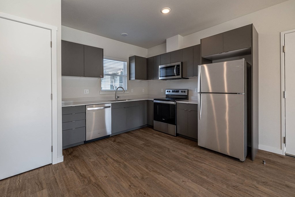 an empty kitchen with stainless steel appliances and gray cabinets at Sagecrest Apartments, Wenatchee, WA, 98801