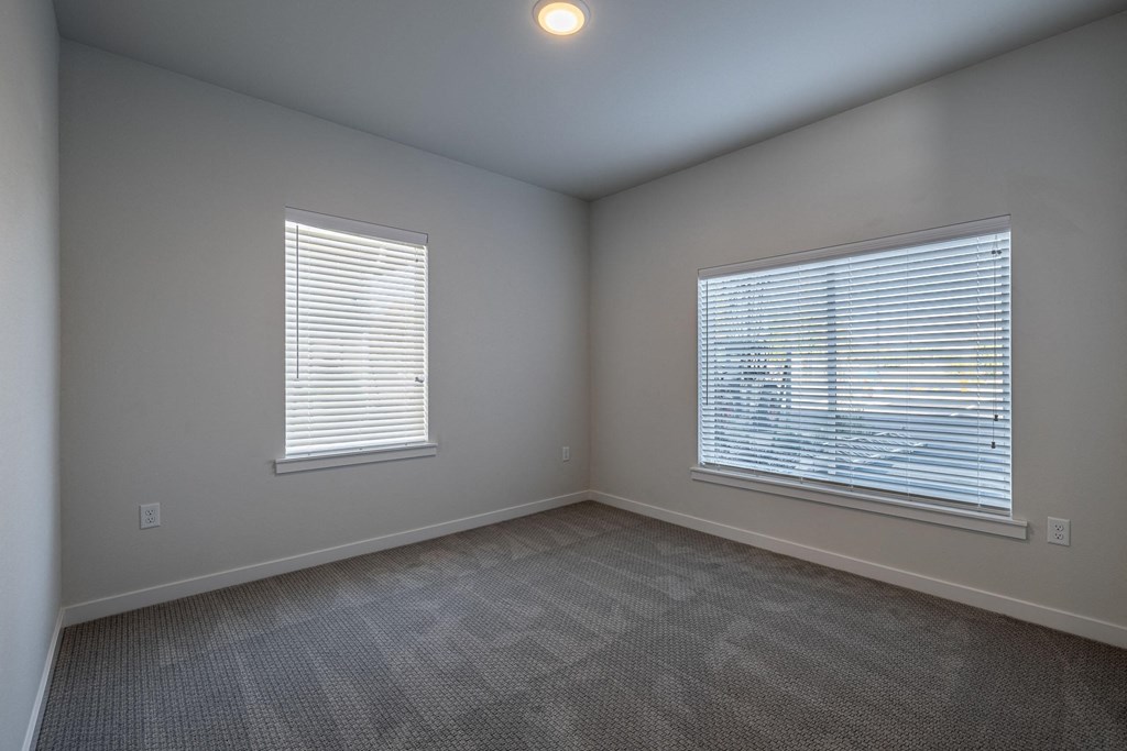 an empty living room with two windows and carpeting at Sagecrest Apartments, Washington