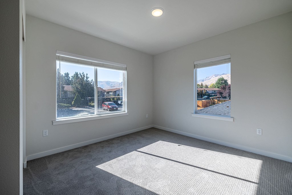 an empty living room with two windows and a rug at Sagecrest Apartments, Wenatchee
