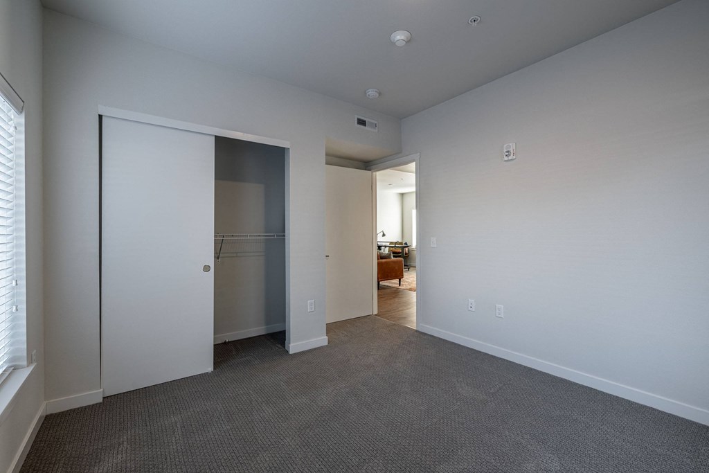 a bedroom with a closet and a door to a living room at Sagecrest Apartments, Wenatchee, WA, 98801