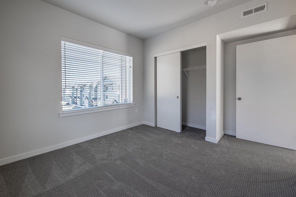 an empty living room with a large window and a door to a closet at Sagecrest Apartments, Wenatchee, WA, 98801