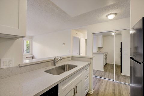 A kitchen with white cabinets and a stainless steel refrigerator.