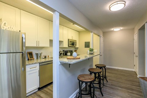 A kitchen with white cabinets and a refrigerator.
