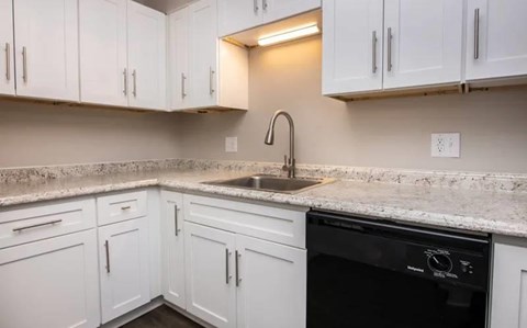 A kitchen with white cabinets and a granite countertop.