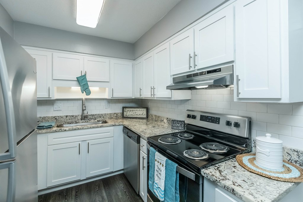 A kitchen with a stove top oven and a refrigerator at Crest at East Cobb Apartments, Georgia, 30062