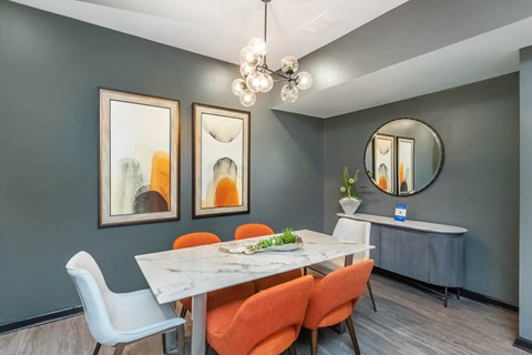 A dining room with a white table and orange chairs.