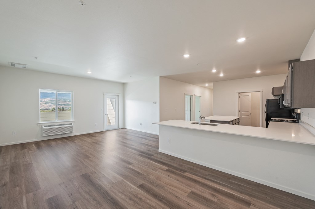 the living room and kitchen of a new home with white walls and wood flooring at Gateway Apartments, East Wenatchee