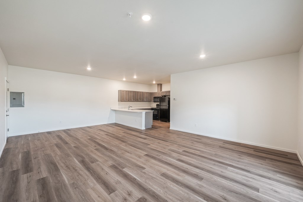 a living room and kitchen with white walls and wood flooring at Gateway Apartments, East Wenatchee