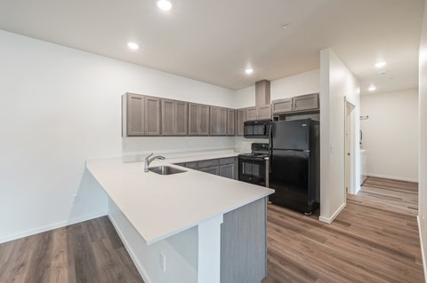 a kitchen with a white counter top and a black refrigerator