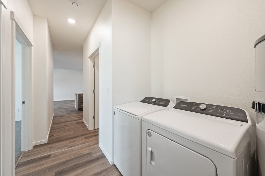 an empty laundry room with two washers and dryers and a hallway with doors at Gateway Apartments, Washington, 98802