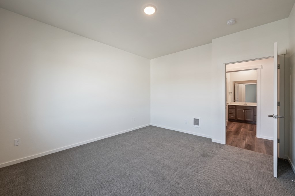 a bedroom with white walls and carpet and a door to a bathroom at Gateway Apartments, Washington, 98802
