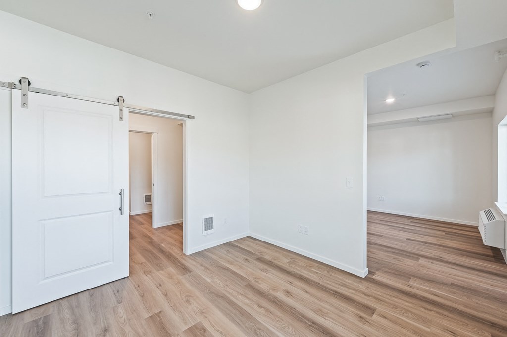 a living room with white walls and wood flooring and a white door at Gateway Apartments, East Wenatchee