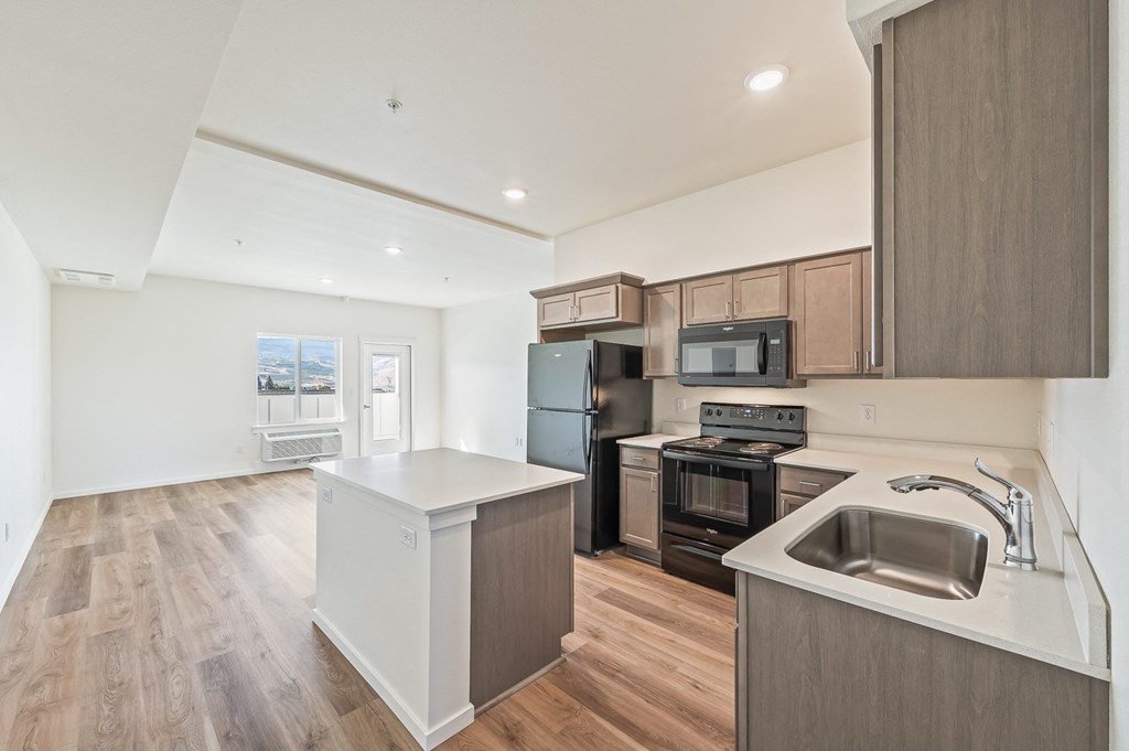 an empty kitchen with a sink and a stove and refrigerator at Gateway Apartments, East Wenatchee , Washington