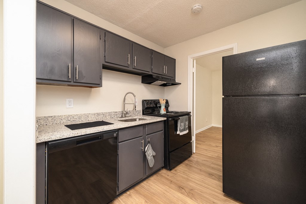 A kitchen with black cabinets and appliances at Overlook Club Apartments, Cummings, 30040