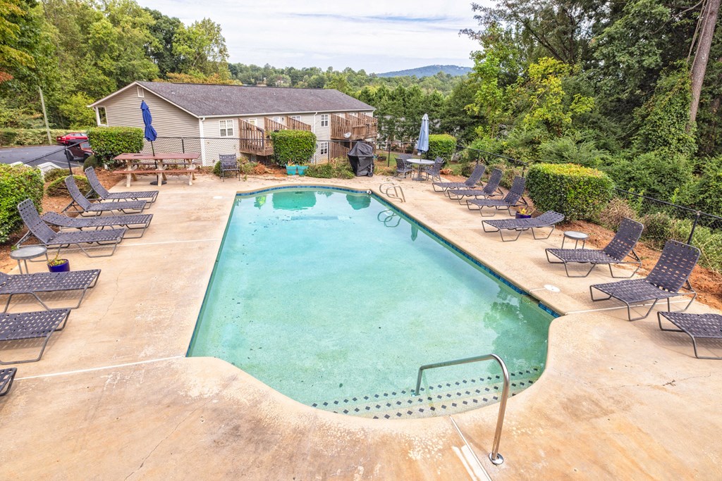 A large outdoor swimming pool surrounded by lounge chairs at Overlook Club Apartments, Cummings, Georgia