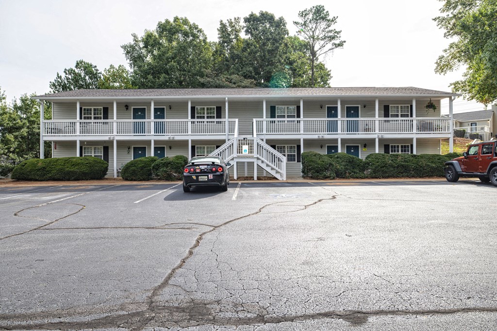 A parking lot in front of a white building with a red truck and a black car at Overlook Club Apartments, Georgia 30040