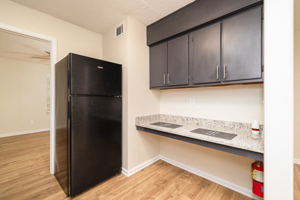 A black fridge in a kitchen with wooden floors and black cabinets at Overlook Club Apartments, Cummings