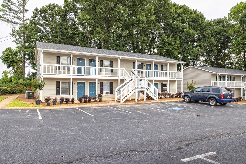 A two-story building with a blue car parked in front at Overlook Club Apartments, Cummings, GA