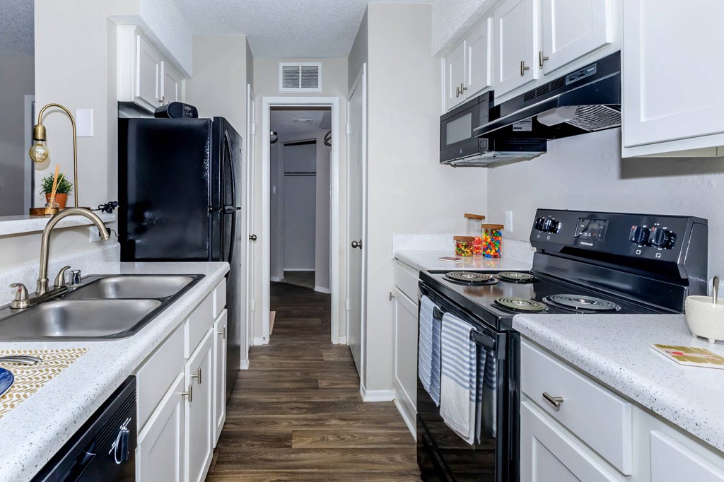 a kitchen with black appliances and white cabinets at The Davis Apartments, Huntsville  