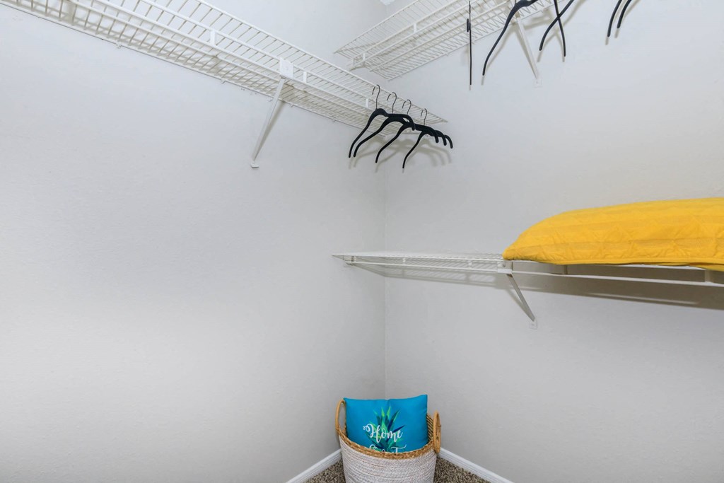 a closet with shelves and a yellow bed in it and a white wall with shelves at The Davis Apartments, Huntsville, AL  