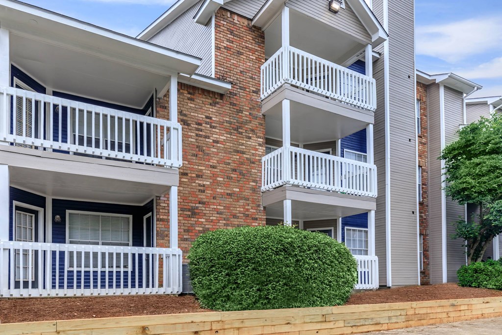 a building with two balconies and a bush in front of it at The Davis Apartments, Huntsville, AL 35816  