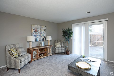 A living room with a grey carpet and furniture.