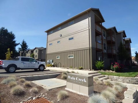 Property entrance sign with landscaping and ornamental grasses at Waln Creek Apartments, Salem, OR 97306