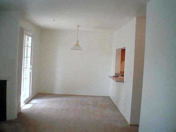 an empty living room with white walls and a ceiling light