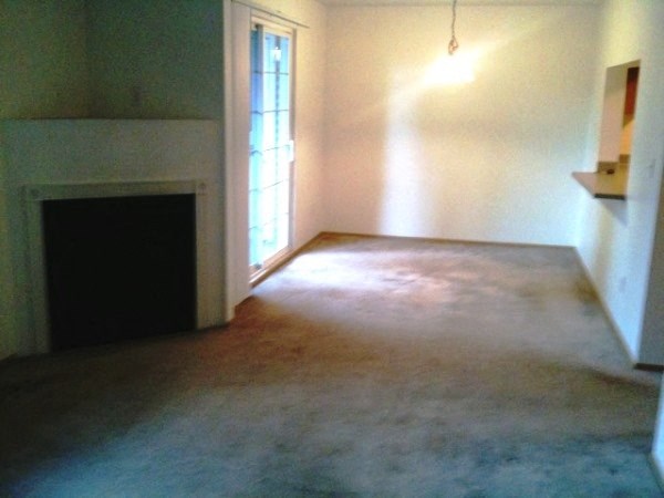 an empty living room with a fireplace and a door