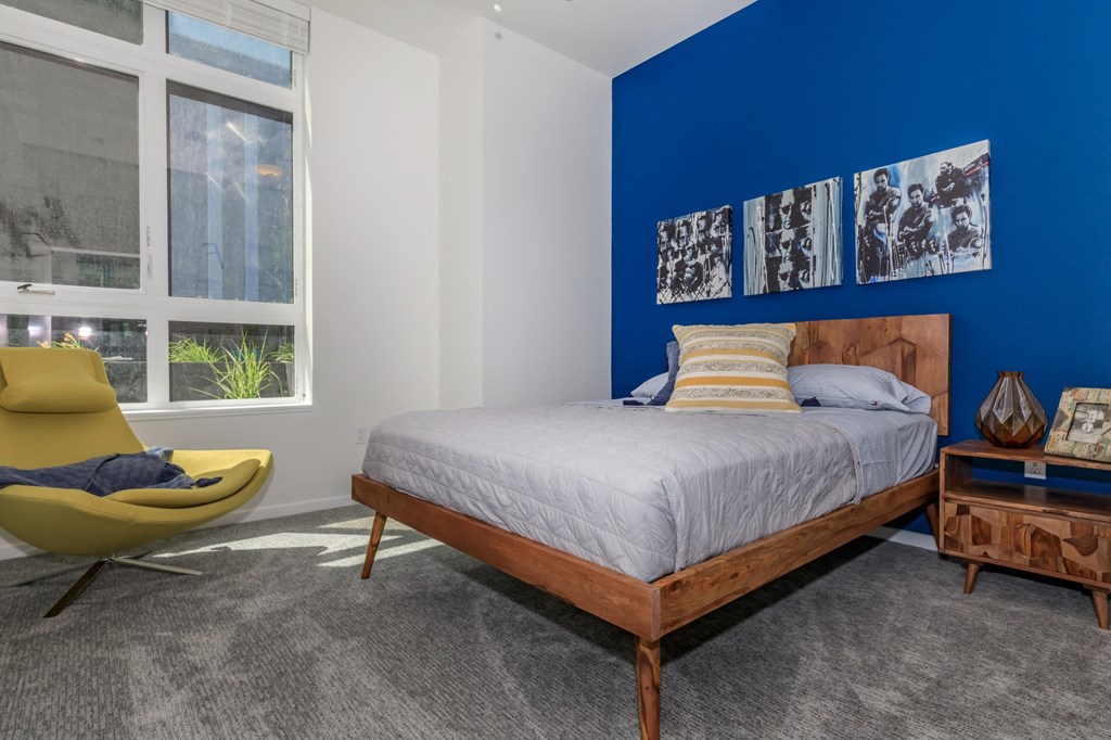 a bedroom with a blue accent wall and a bed with a wooden headboard a bedroom with a blue accent wall and a bed with a wooden headboard at Napoleon Apartments, Tacoma, WA