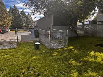 A fenced area with a trash can and a sign at Ironwood Apartments, Coeur d'Alene