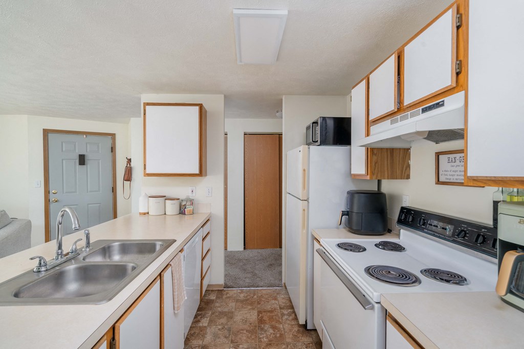 a kitchen with a white refrigerator freezer next to a white stove top oven a kitchen with a white refrigerator freezer next to a white stove top oven at Ironwood Apartments, Coeur d'Alene, 83814