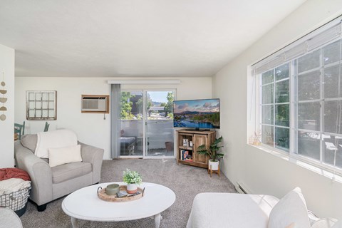 a living room with two couches a coffee table and a sliding glass door to a balcony