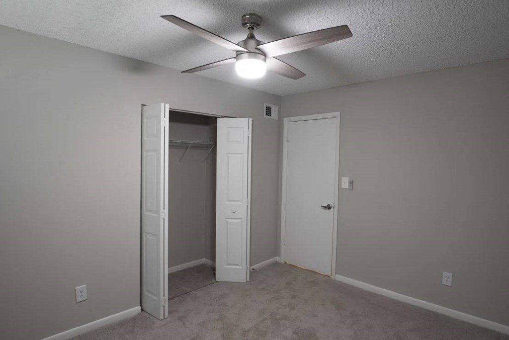 A room with a ceiling fan and two doors at The Madison Apartments and Townhomes, Lawrenceville, GA
