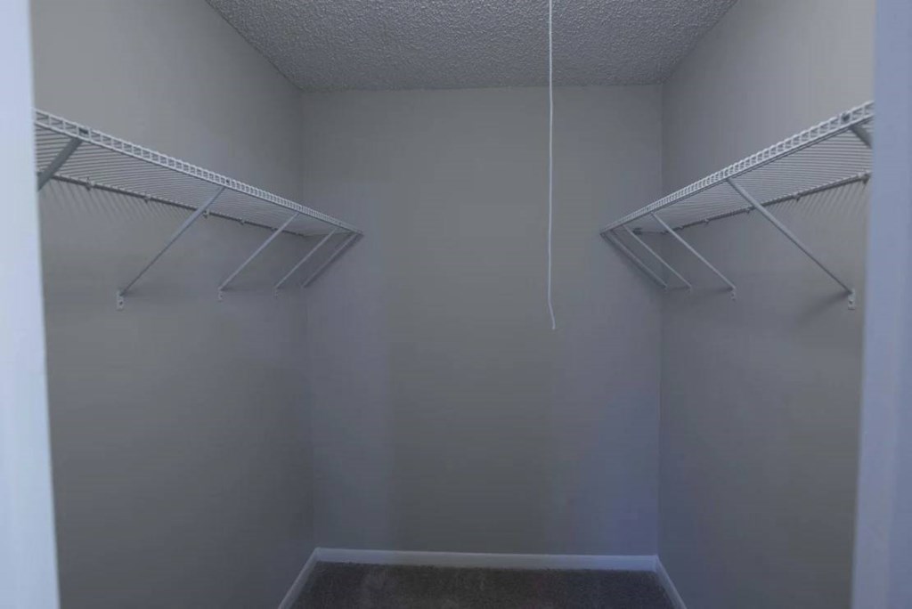 Empty walk-in closet with white shelves and a white ceiling at The Madison Apartments and Townhomes, Lawrenceville, GA, 30044