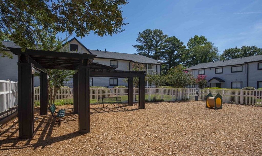 A gravel area with a wooden structure and a fence in the background at The Madison Apartments and Townhomes, Lawrenceville, GA