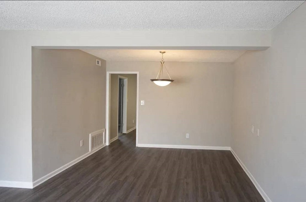 A room with a wooden floor and a light hanging from the ceiling at The Madison Apartments and Townhomes, Georgia 30044