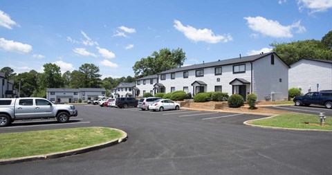 A parking lot with cars and a building in the background at The Madison Apartments and Townhomes, Lawrenceville, GA
