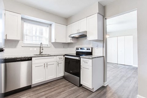 A kitchen with white cabinets and a black countertop.