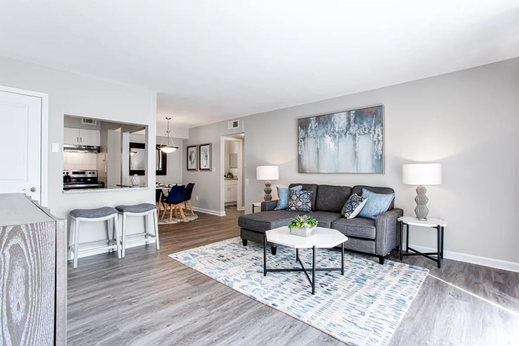 A living room with a grey couch, a white coffee table, and a painting on the wall at Barcelo at East Cobb Apartments, Marietta