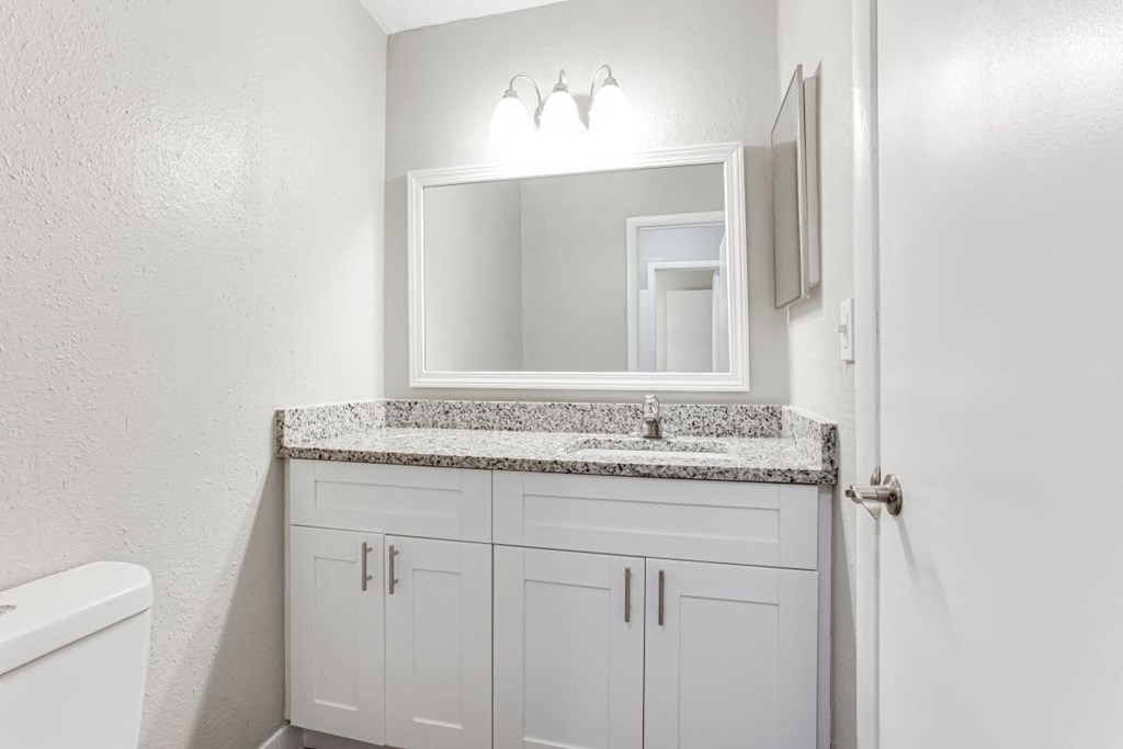 A bathroom with a granite countertop and white cabinets at Barcelo at East Cobb Apartments, Marietta, GA, 30067
