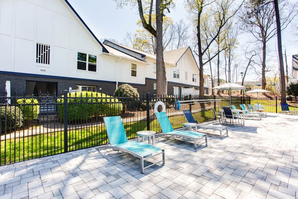 A white building with a black fence and blue chairs in front at Barcelo at East Cobb Apartments, Marietta, GA
