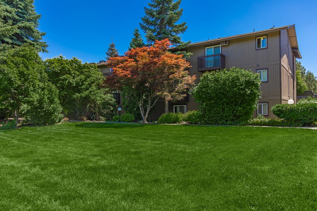 an apartment building with green grass and trees in front of it an apartment building with green grass and trees in front of it at Lincoln Village Apartments, Washington
