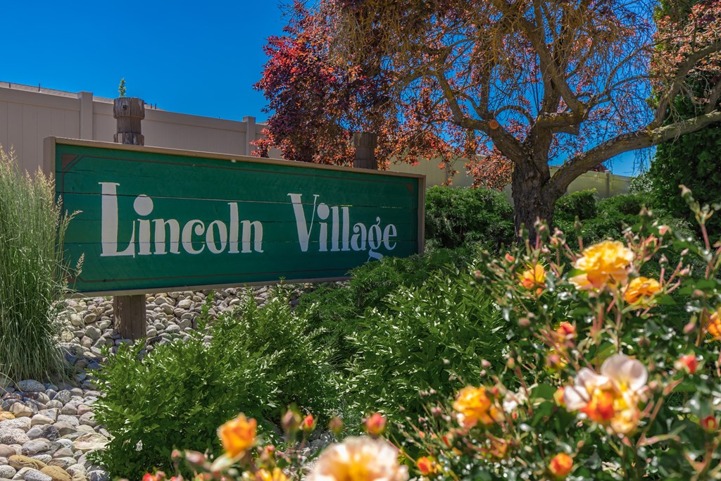 a sign village in front of a garden of flowers at Lincoln Village Apartments, Washington, 99208