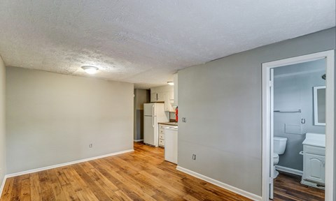 A room with wooden floors and a white ceiling with a kitchen area visible through the door.at Waverly Manor Townhomes, Norcross, 30071