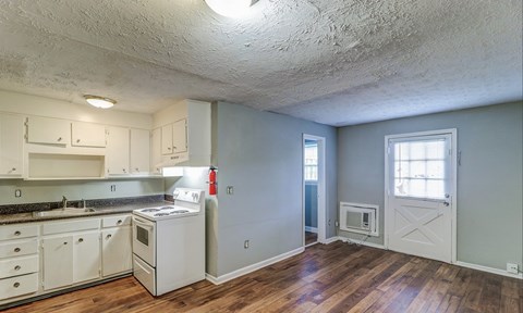 A kitchen with white cabinets and a white stove top oven.