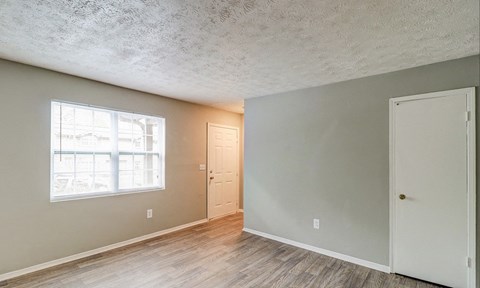 A room with a window, two doors, and a wooden floor.at Waverly Manor Townhomes, Georgia