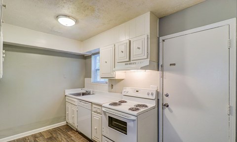 A kitchen with white appliances and cabinets.at Waverly Manor Townhomes, Norcross