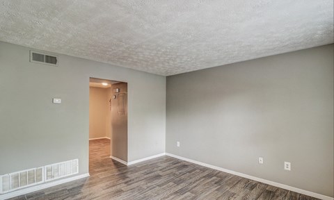 A room with a wooden floor and a white wall with a doorway leading to another room.at Waverly Manor Townhomes, Norcross Georgia