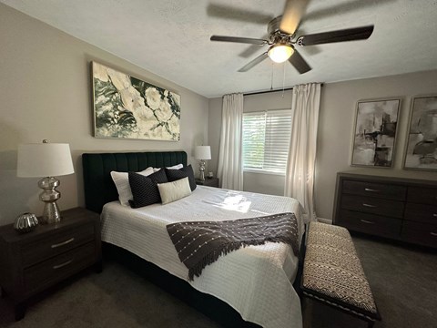A bedroom with a bed, nightstand, and a ceiling fan at Chelsea Place Apartments, Lithonia, GA, 30058
